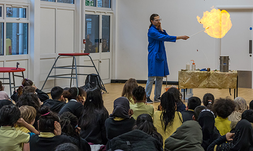 A researcher creating a ball of fire for a room of primary school children